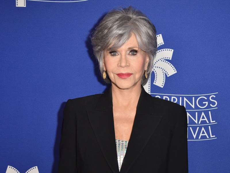 close up of Jane Fonda with a neutral expression wearing a black dress jacket and silver blouse