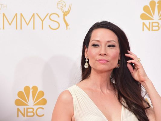 Lucy Liu in a white dress and drop earrings at the 2014 Emmy Awards