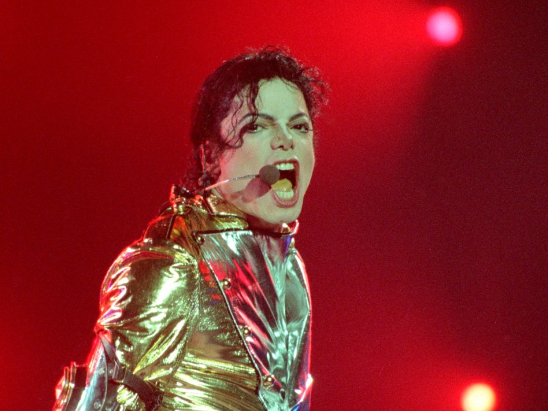 1996 photo of Michael Jackson singing on stage in a gold jacket
