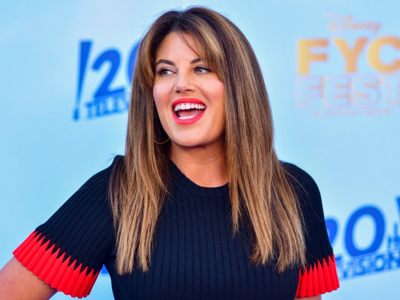 Monica Lewinsky smiles in navy blue dress with red trim