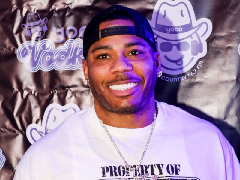 Nelly smiling with black baseball cap on backwards and a white tee shirt