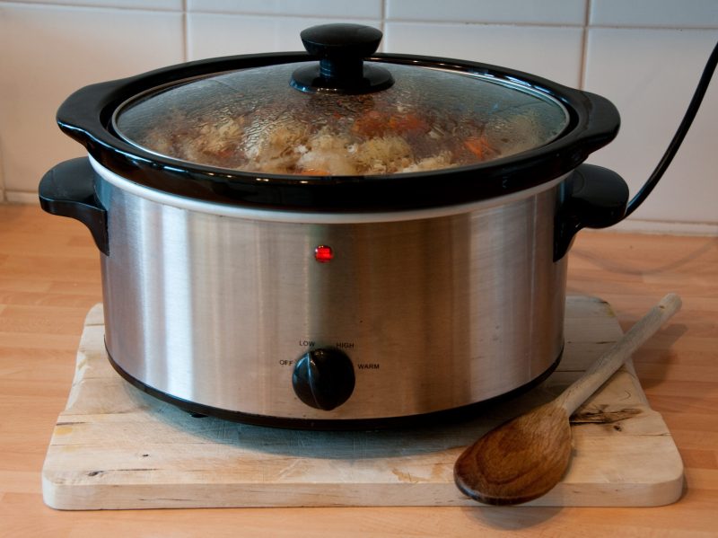 A slow cooker plugged in and cooking a meal