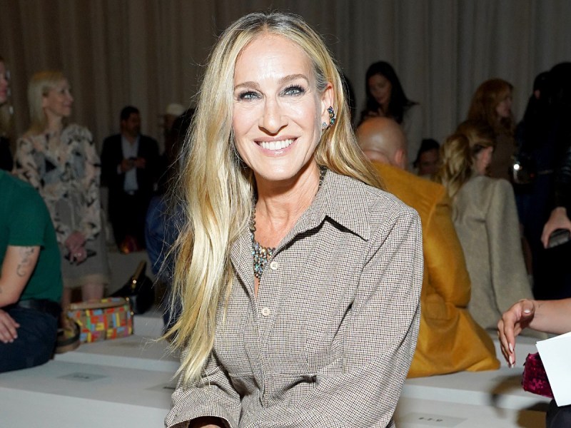 Sarah Jessica Parker sits and smiles in beige jacket