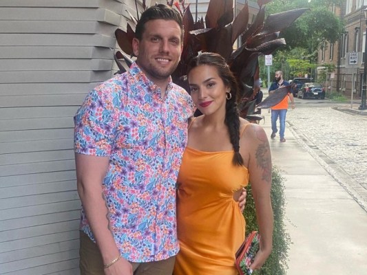Chris Distefano (L) and his wife, Jazzy posing outside in brightly colored clothing