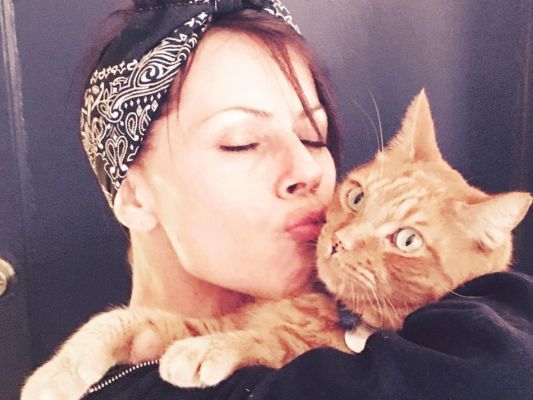 Fairuza Balk wearing a bandana in her hair and holding an orange cat