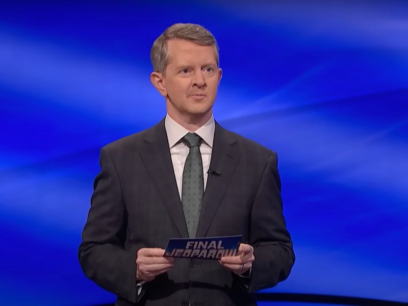 screenshot of Ken Jennings hosting Jeopardy! in a gray suit
