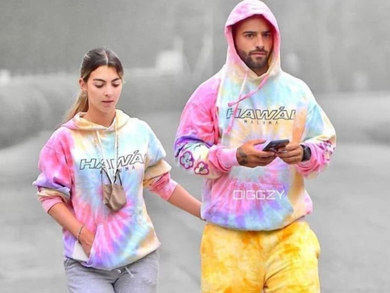 Maluma (R) and his girlfriend Susana Gomez walking together wearing matching tie-dye hoodies