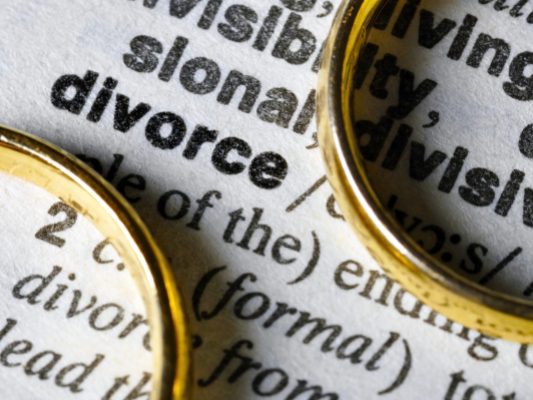 Paper with the definition of divorce and two gold rings on top.