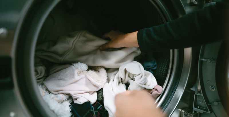 Woman Putting Clothes In Washing Machine